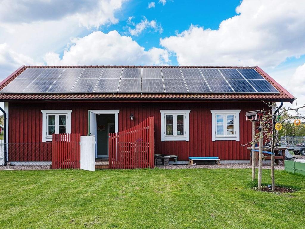 una casa roja con paneles solares en el techo en 2 person holiday home in RIMFORSA en Rimforsa