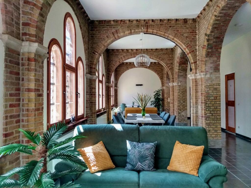 uma sala de estar com um sofá verde numa parede de tijolos em Pilgrim's Loft em Ieper
