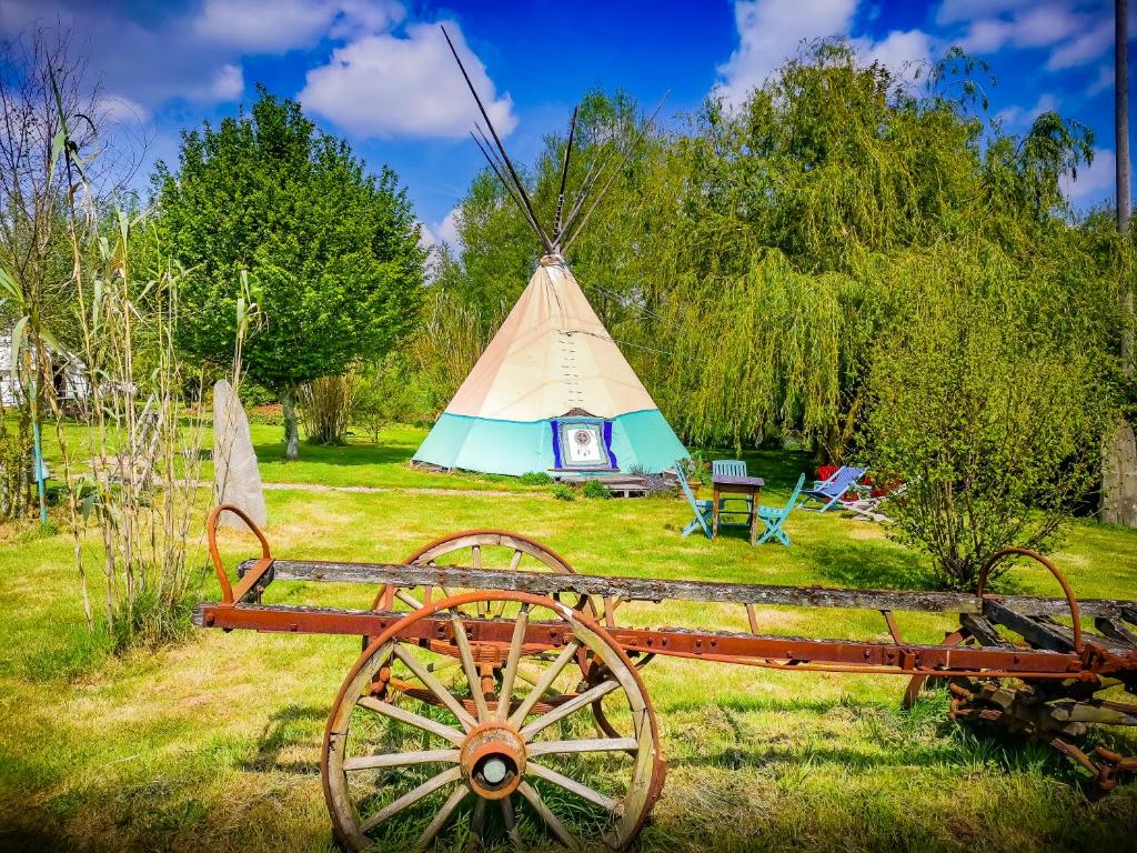 a yurt with a wooden cart in the grass at Au Bonheur Nomade in Livry