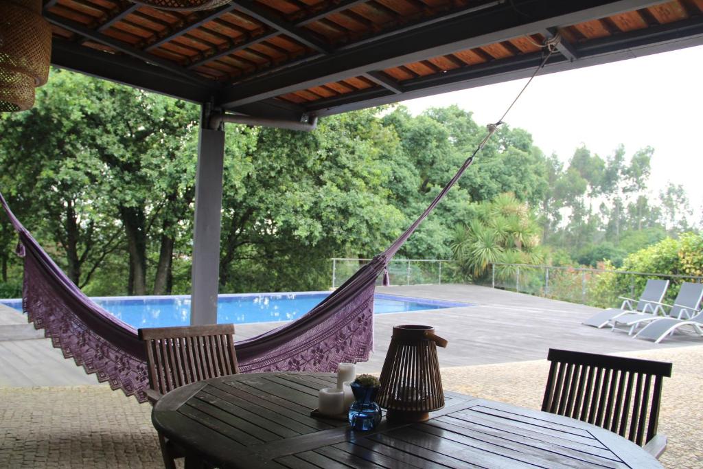 eine Hängematte auf einer Terrasse mit einem Tisch und Stühlen in der Unterkunft Porto-Braga Country side - private swimming pool in Alvarelhos