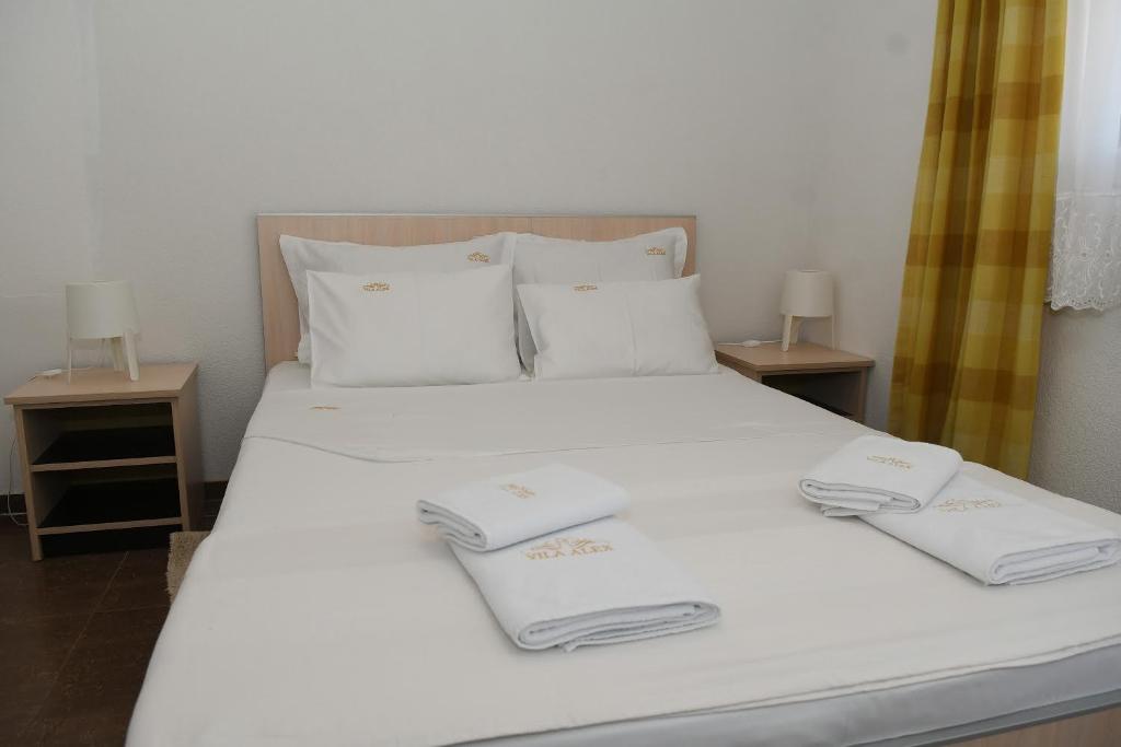 Una cama blanca con dos toallas blancas. en Sobe Alex en Veliko Gradište