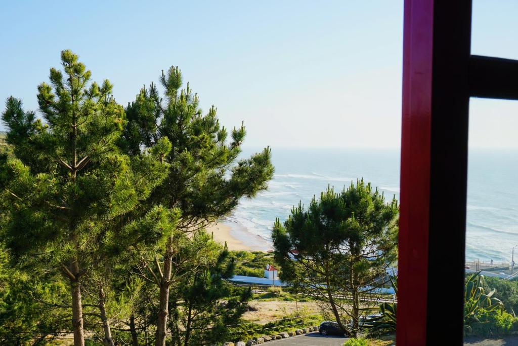 a view from a window of trees on the beach at Magoito Beach Apartment in Sintra
