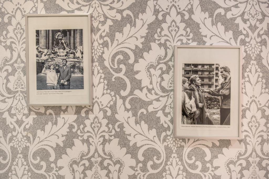 three framed photographs on a wall with wallpaper at Marta Inn in Rome
