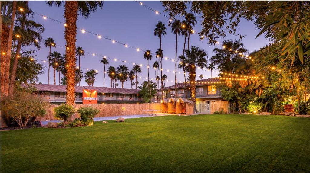 ein Haus mit einem Hof mit Palmen und Lichtern in der Unterkunft Caliente Tropics in Palm Springs