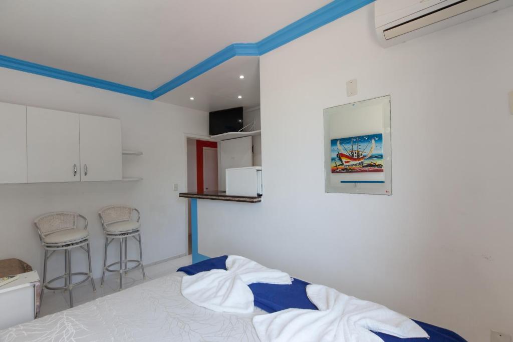 a bedroom with a white bed and white walls at Pousada Águas do Mariscal in Bombinhas