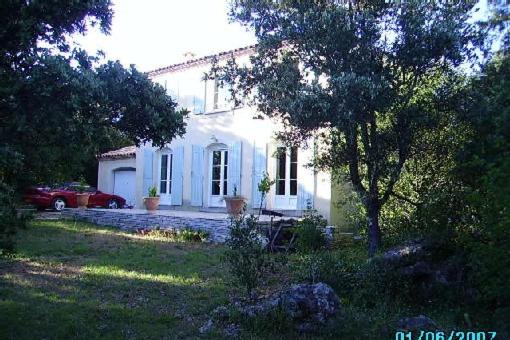 une maison blanche avec une voiture garée devant elle dans l'établissement BASTIDE DE CHARME PISCINE PRIVATIVE GORGES HERAULT, à Le Causse-de-la-Selle