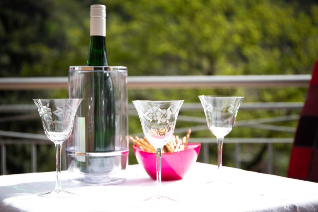 una botella de vino y tres copas de vino en una mesa en Ferienwohnung Liomena en Lehmen