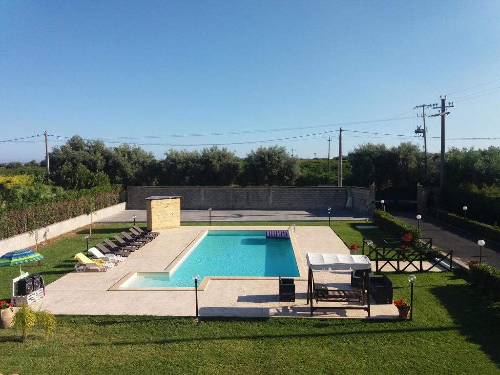 a swimming pool in a yard next to a field at Villa Stefy apartments in Avola