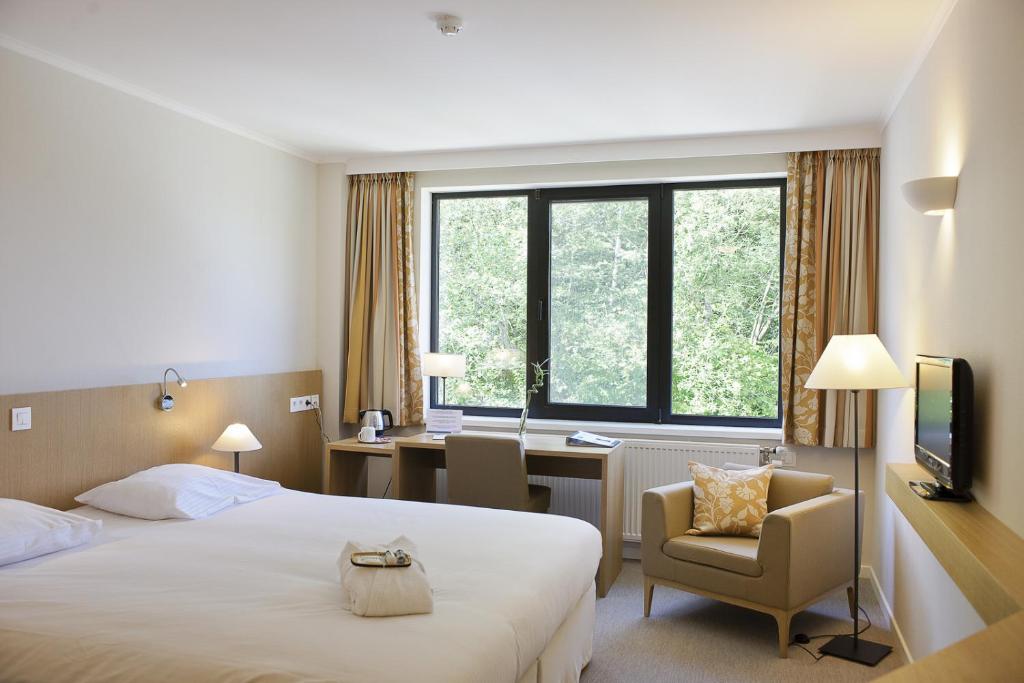 una camera d'albergo con letto, sedia e scrivania di Château du Haut-Neubois a Spa
