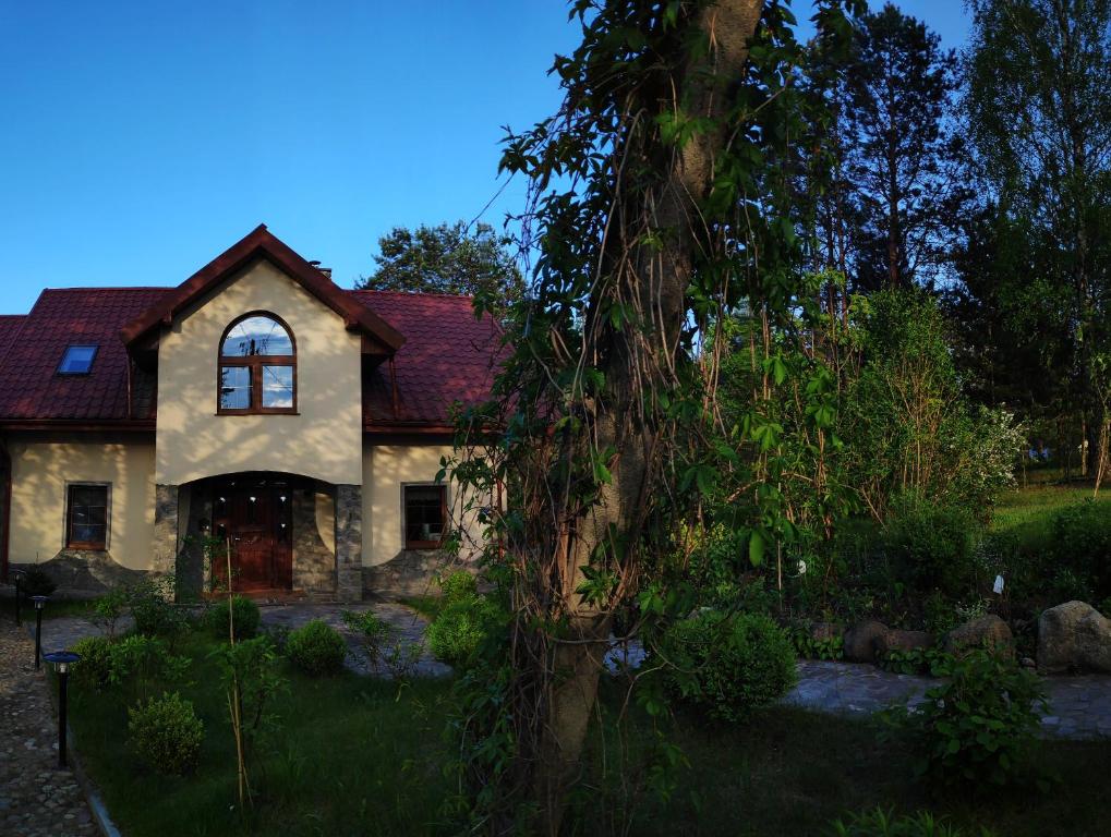 a house with a tree in front of it at Domek Leśna Przystań in Strękowizna