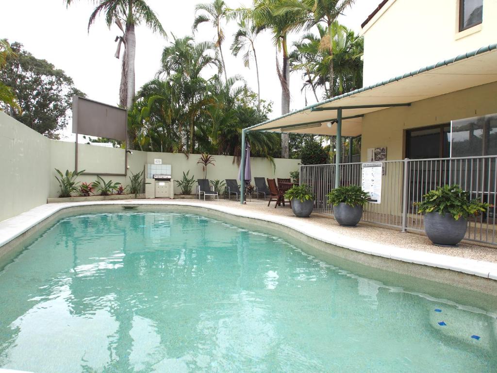 a swimming pool in front of a building with palm trees at Le Court Villas in Noosa Heads