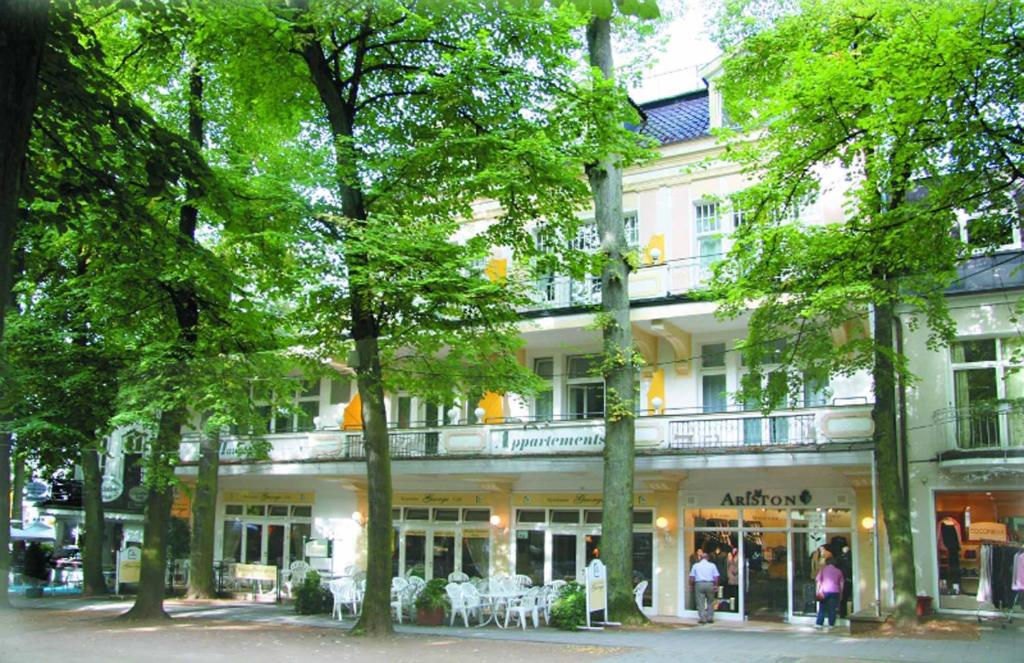 un grand bâtiment blanc avec des arbres devant lui dans l'établissement Hauptallee Appartements, à Bad Pyrmont