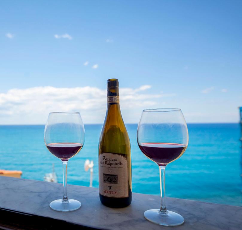 uma garrafa de vinho e dois copos numa mesa em Blue Coral Apartment em Cefalù