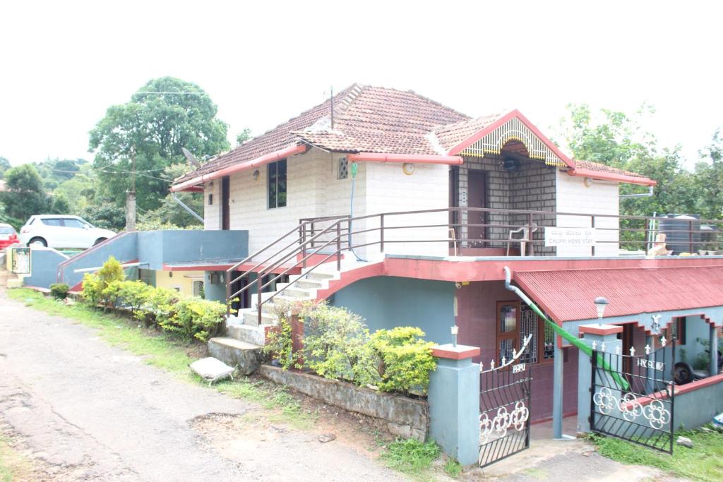 a white house with a red roof and a porch at Chuppi Homestay in Madikeri