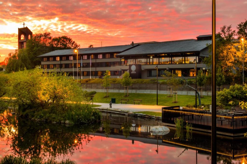 un edificio al atardecer con un reflejo en el agua en Hotell Jæren, en Bryne