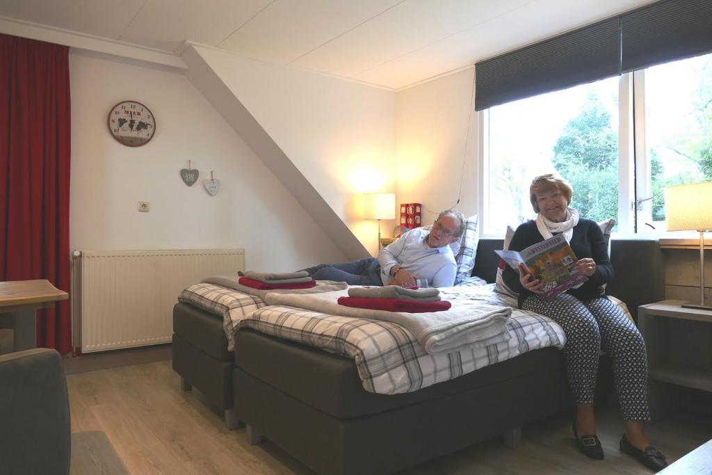 Due donne sedute su un letto in una stanza di B&B OpdeParkkamp met laadpaal voor elektrische auto's a Havelte
