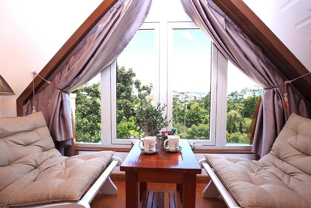 a living room with a table and a large window at Dan Chi Hotel in Da Lat