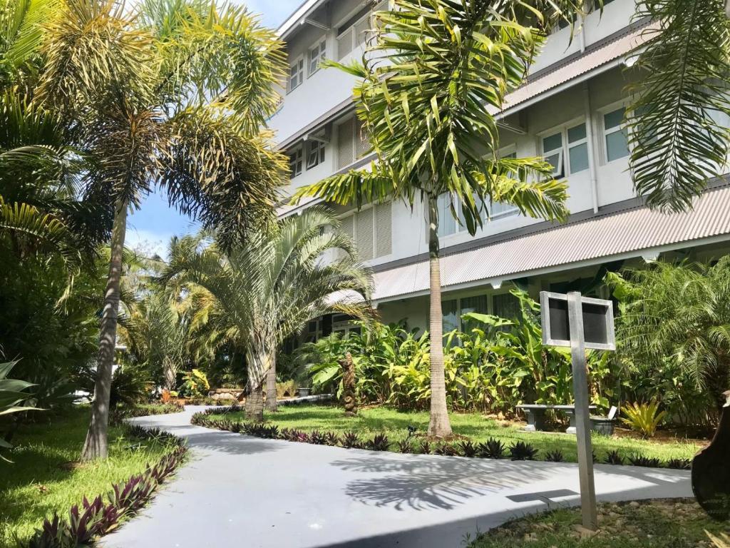 a walkway in front of a building with palm trees at Hotel Beaurivage in Noumea