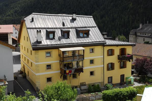 un grande edificio giallo con tetto in metallo di Chasa Marugg - Ferienwohnung für 4-5 Personen, 70m2 a Scuol