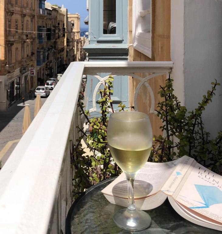 a glass of wine sitting on a table on a balcony at Merchants Street Valletta Apartment in Valletta