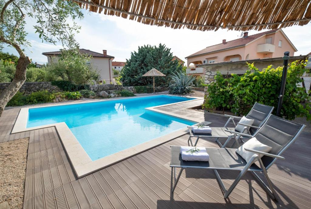 a swimming pool in a backyard with two chairs and a table at Villa Čimić in Krk
