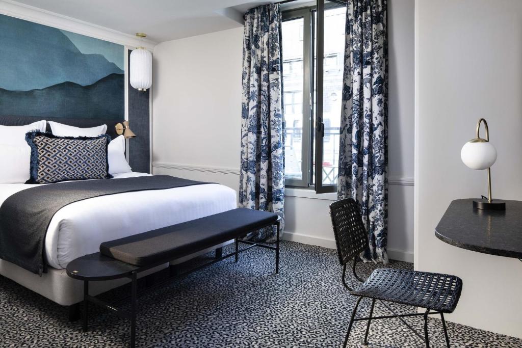 um quarto com uma cama, uma cadeira e uma janela em Hôtel Gramont em Paris