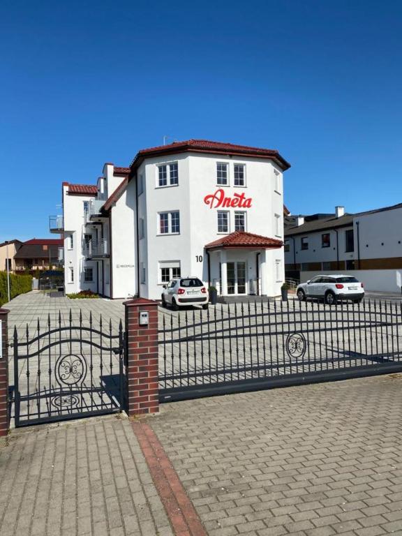 a white building with a fence in front of it at Aneta in Grzybowo