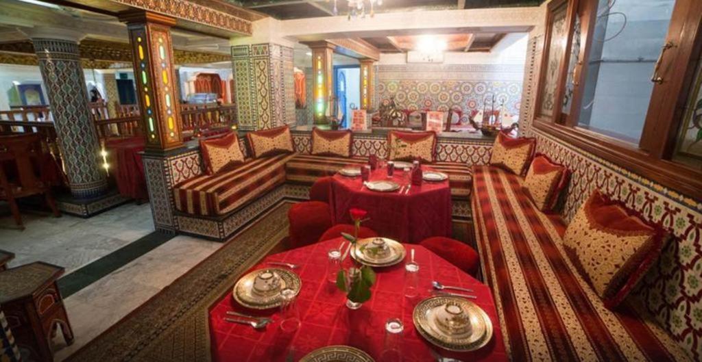un restaurant avec des tables et des chaises rouges dans une salle dans l'établissement Hotel Moroccan House Casablanca, à Casablanca