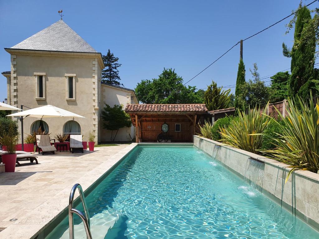 a swimming pool in front of a house at Domaine de Larchey & son restaurant - Bordeaux Sud in Saint-Médard-dʼEyrans