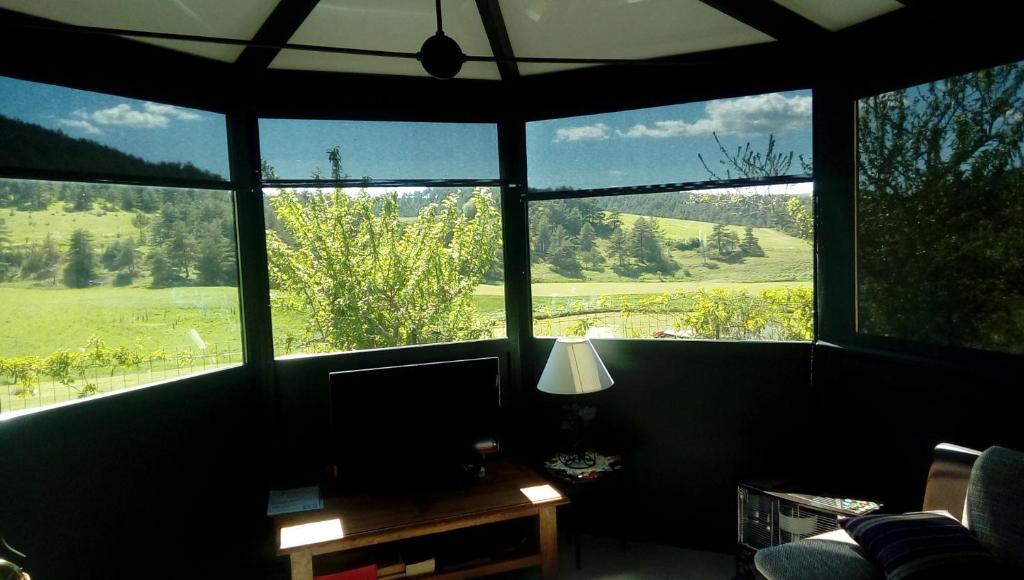 Habitación con ventanas grandes, escritorio y TV. en Chez Louis chambres d'hôtes à la ferme, en La Canourgue