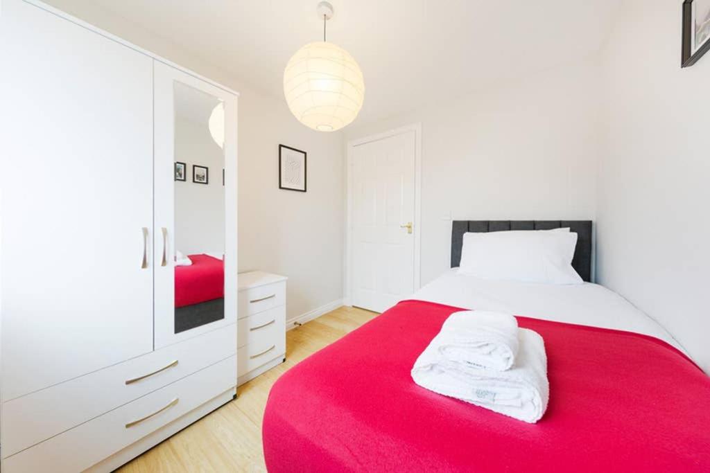 a white bedroom with a red bed and a mirror at Bristol 2 Bedroom Apartment FREE PARKING in Bristol