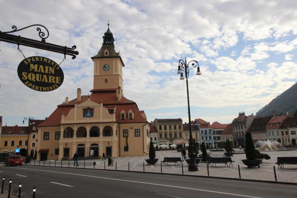 a large building with a clock tower on a street at Main Square Apartments & More in Braşov
