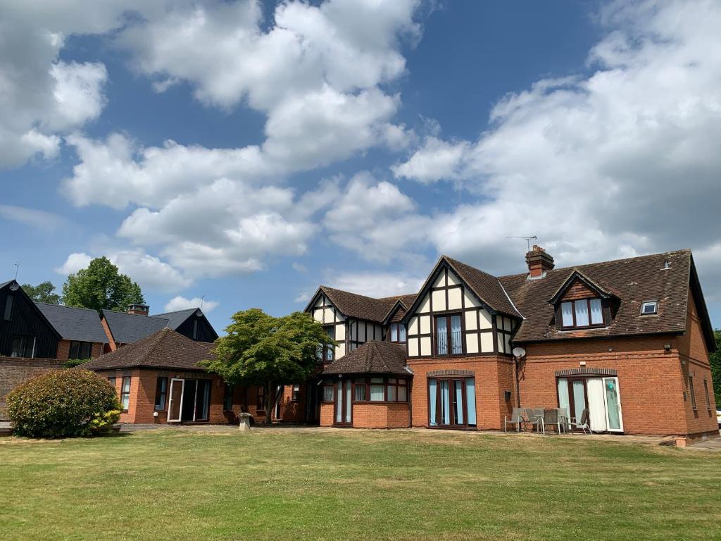 une grande maison en briques sur une pelouse dans l'établissement Badgemore Park, à Henley-on-Thames