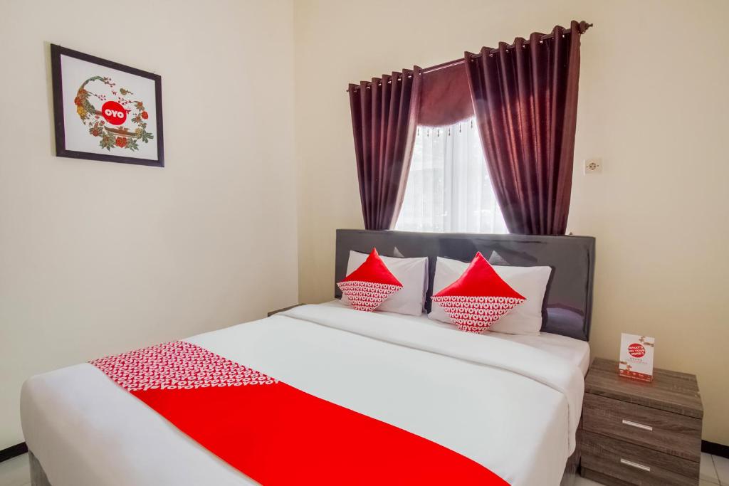 a bedroom with a bed with red pillows and a window at Super OYO 2771 D'soetta in Malang