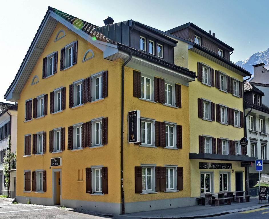 ein gelbes Gebäude mit vielen Fenstern auf einer Straße in der Unterkunft Hotel Freihof in Glarus