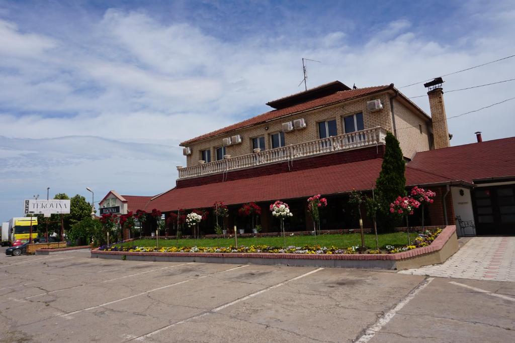 een gebouw met veel bloemen op een parkeerplaats bij Guesthouse & restaurant Tekovina in Smederevo