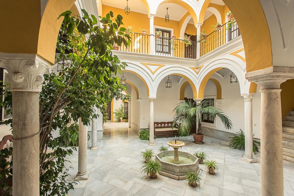 a building with a courtyard with a fountain and plants at Mágico apartamento en casa palacio del siglo XVII in Seville