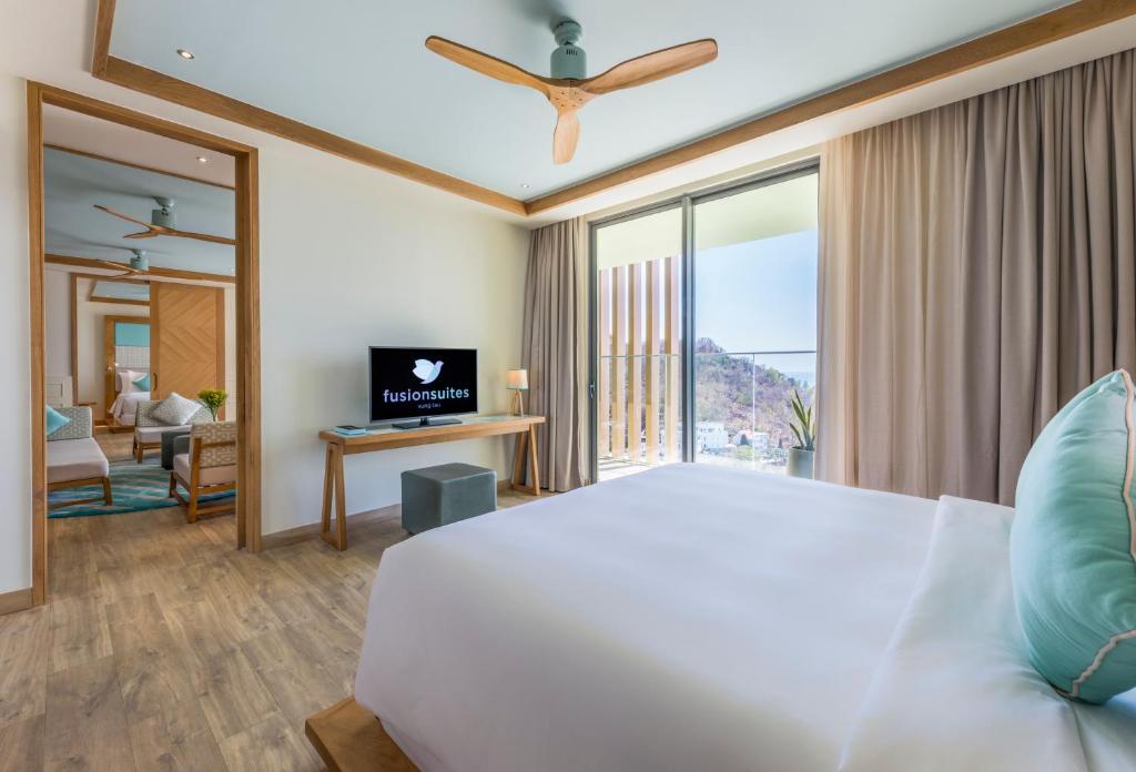 a bedroom with a white bed and a large window at Fusion Suites Vung Tau in Vung Tau