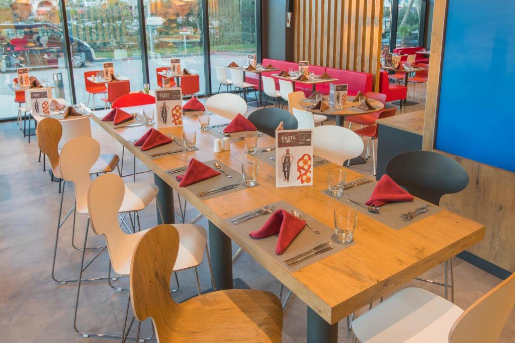 a dining room with tables and chairs with red napkins at ibis Alger Aéroport in Alger