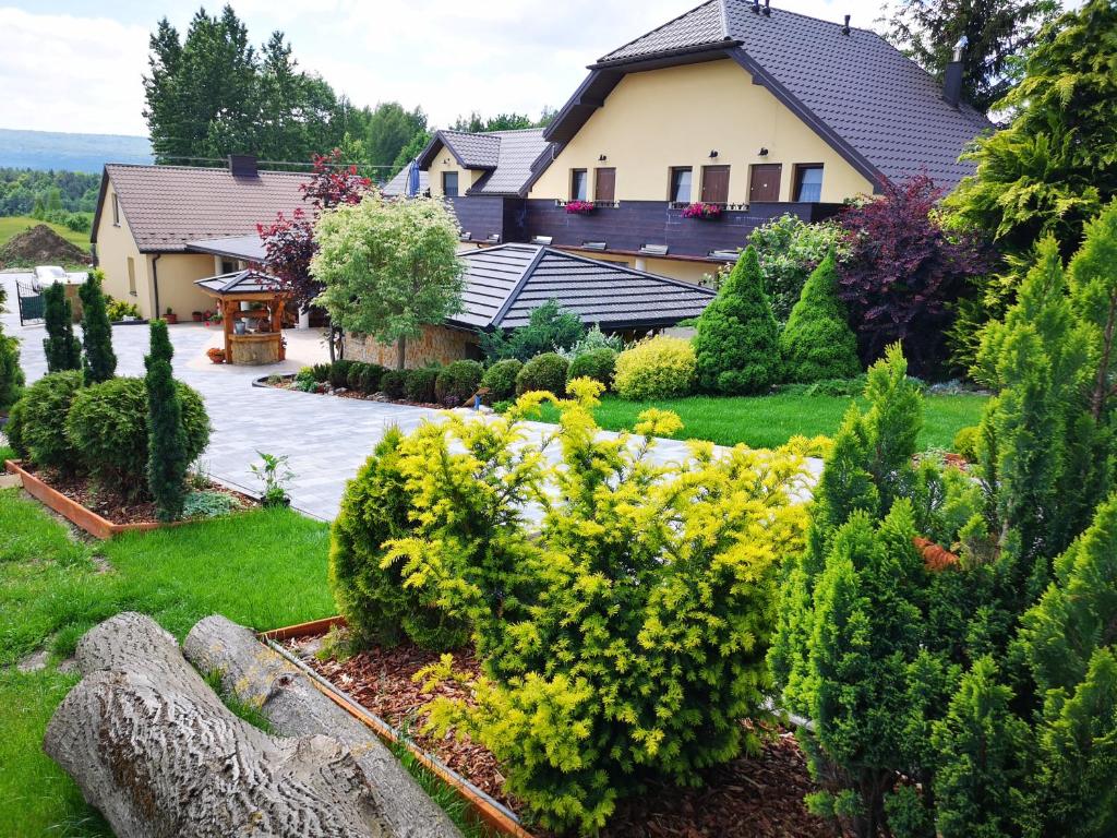 a house with a garden with bushes and trees at Magiczny Zakątek in Dąbrowa