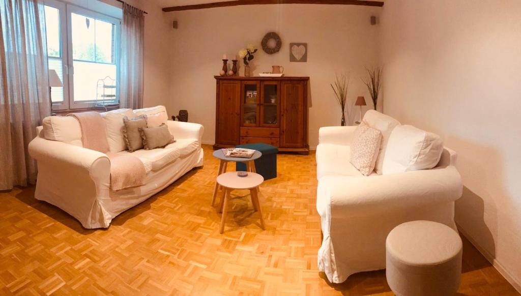 una sala de estar con 2 sofás blancos y una mesa. en Ferienwohnung Jette mit Wallbox, en Hanstedt