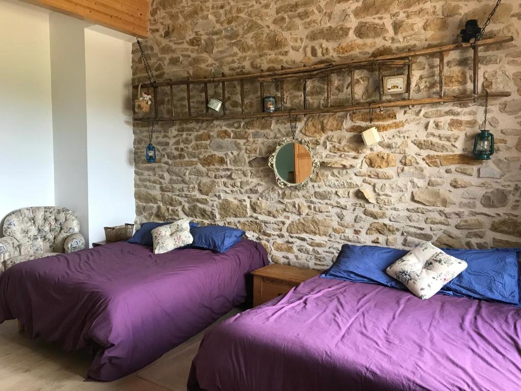 two beds in a room with a stone wall at Domaine du Colombier, Gite La Liberte in Larroque