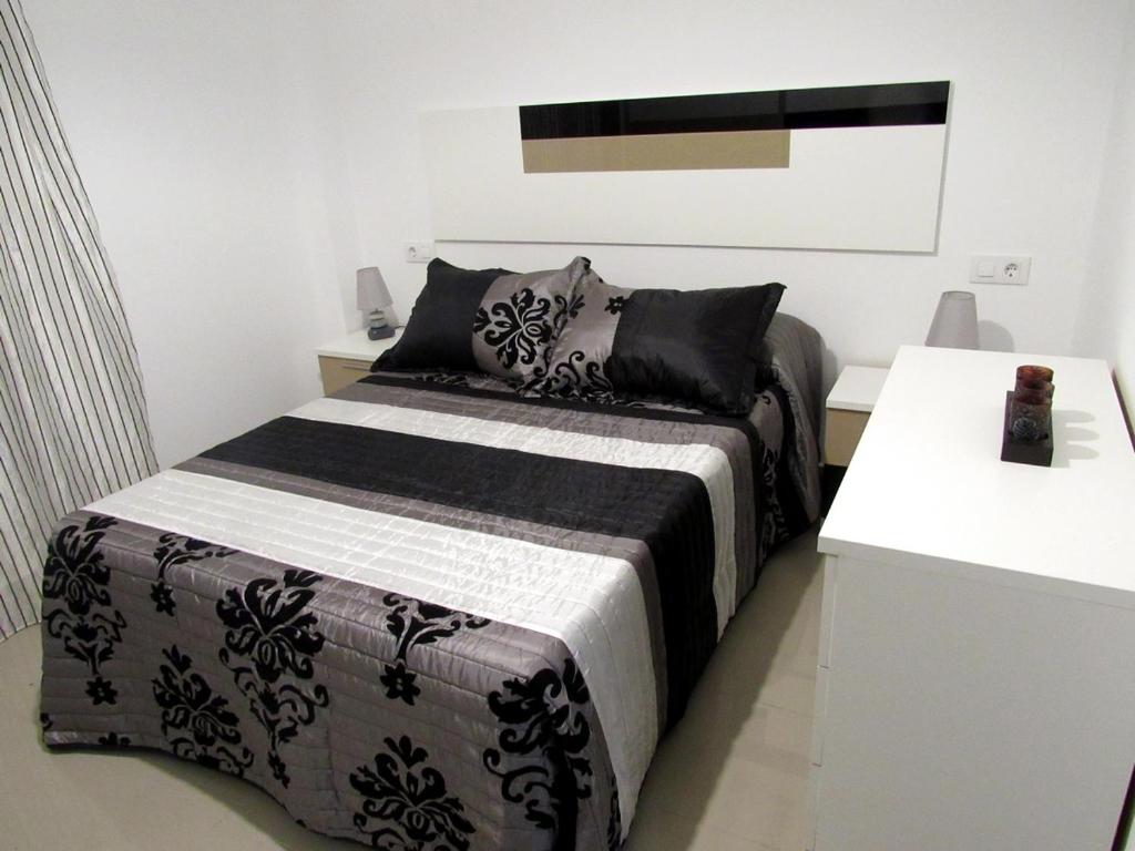 a bedroom with a bed with a black and white blanket at Apartamentos La Bodega in La Zarza