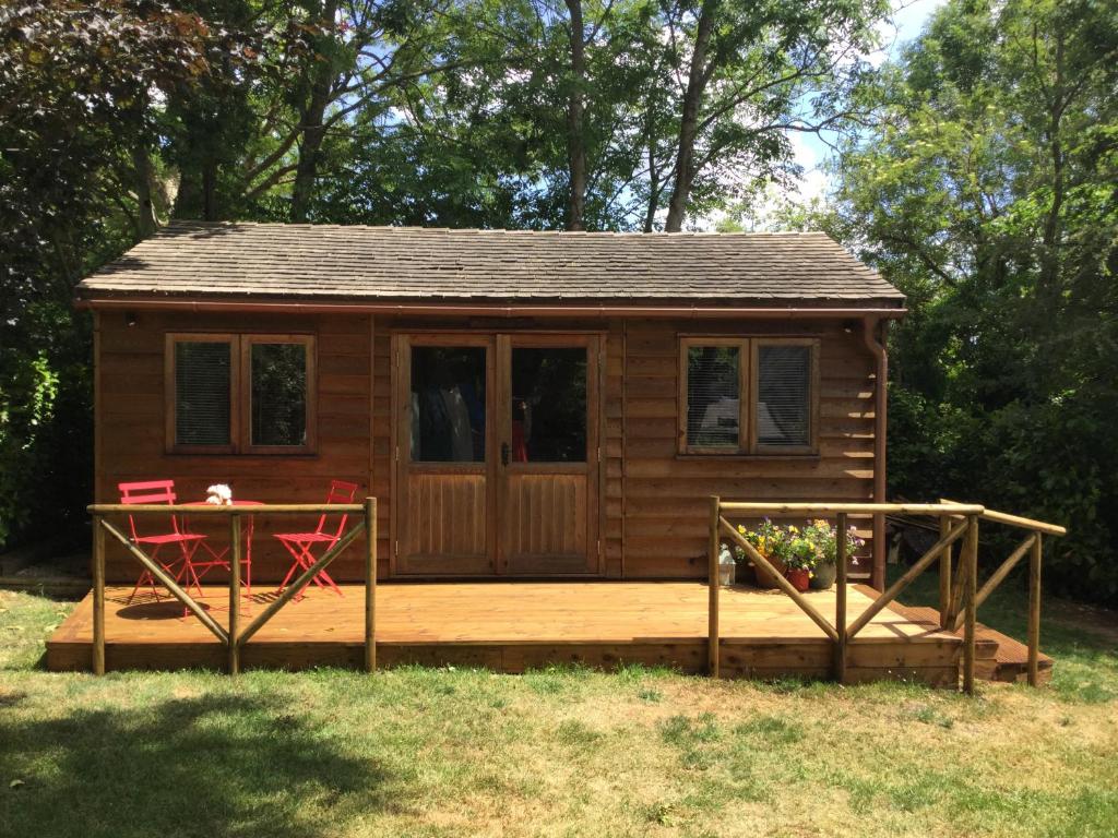 a small cabin with a deck and two red chairs at PieNook in Blandford Forum