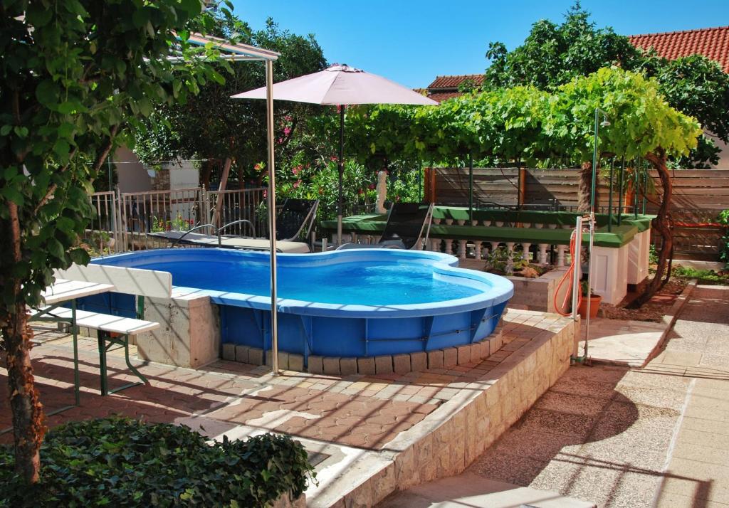 einen Pool im Garten mit einem Sonnenschirm und einem Tisch in der Unterkunft Toni in Vodice