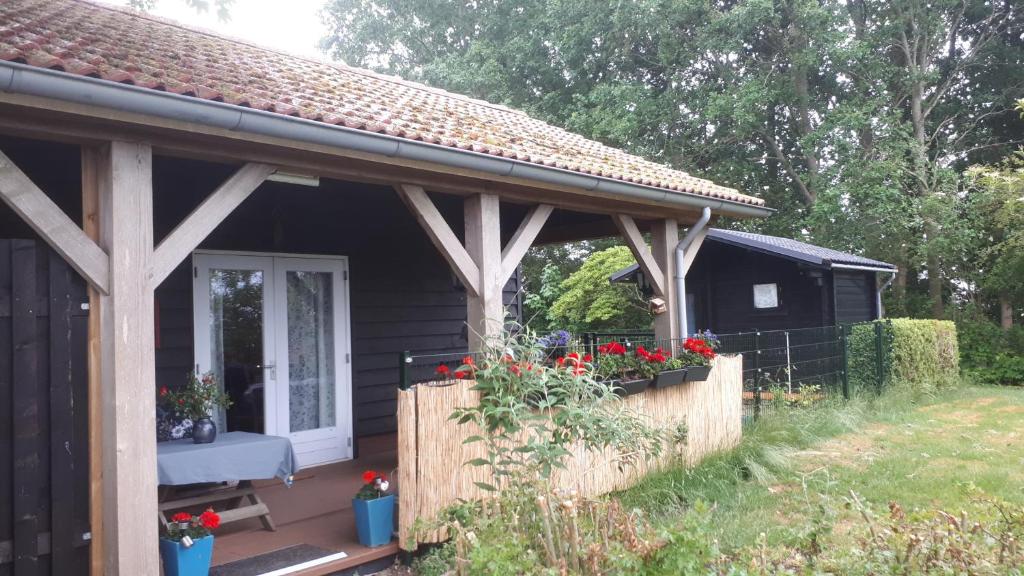 una casa con un porche con flores en un patio en B&B 't Lierderholt, en Lierderholthuis