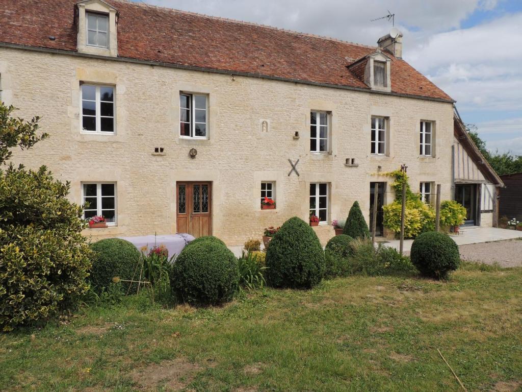 a large brick house with bushes in front of it at La Ferme du Bourg in Éraines