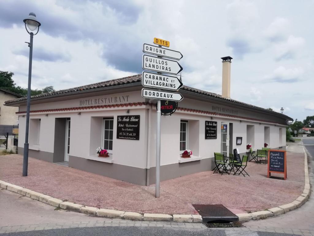 un palo con segnali stradali di fronte a un edificio di Le Merle Blanc Louchats a Louchats