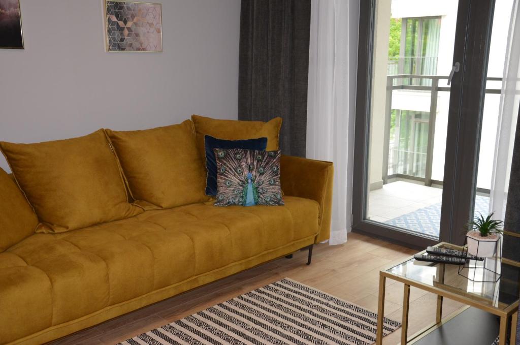 a brown couch in a living room with a glass table at Długie Ogrody Apartment 140 Gdańsk in Gdańsk