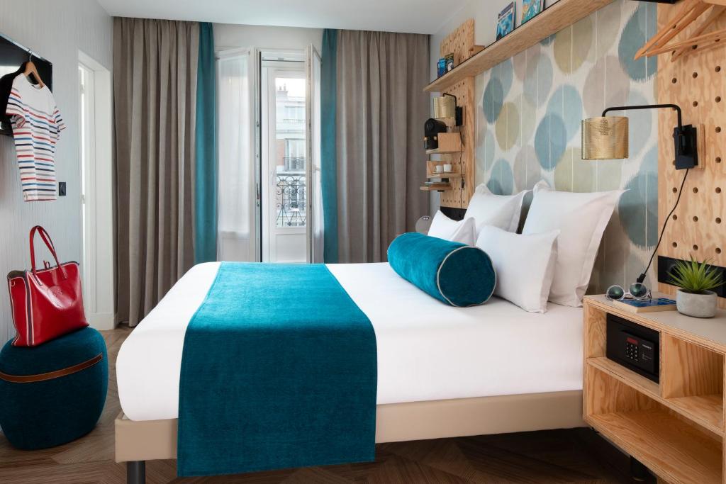 um quarto de hotel com uma cama grande e um cobertor azul em Hôtel LOCOMO em Paris